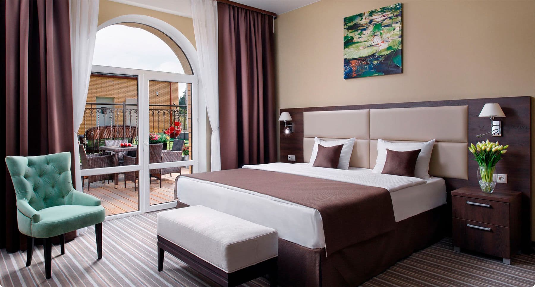 Уютный гостиничный номер с двуспальной кроватью, террасой и стильным интерьером в теплых тонах.